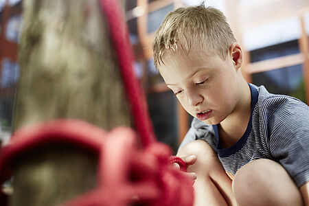 Ein Kinde knotet konzentriert ein Seil