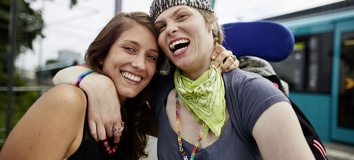 Zwei junge Frauen lachen Arm in Arm